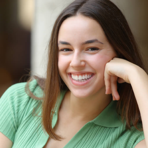 Patient holding up a dental shade guide guide to her teeth
